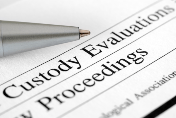 Close-up of a pen resting on a document titled 'Custody Evaluations' with blurred text in the background.