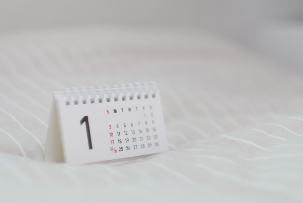 A small white calendar on a soft white surface. The calendar is open to January