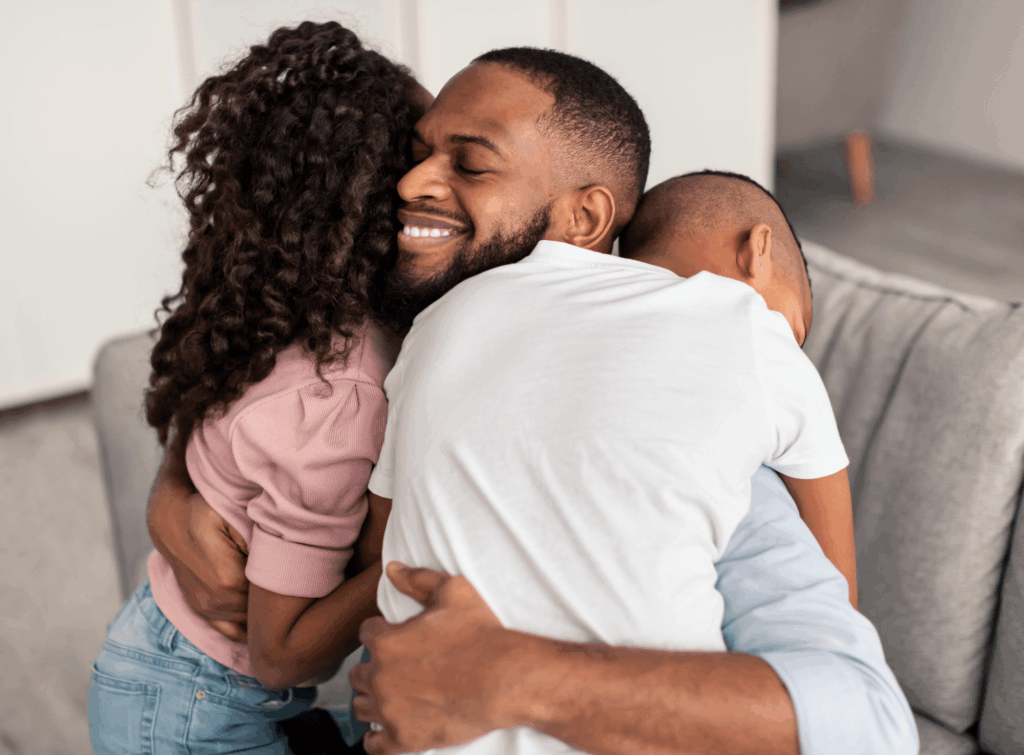 Man hugging his children with a smile on his face after regaining custody of his children.