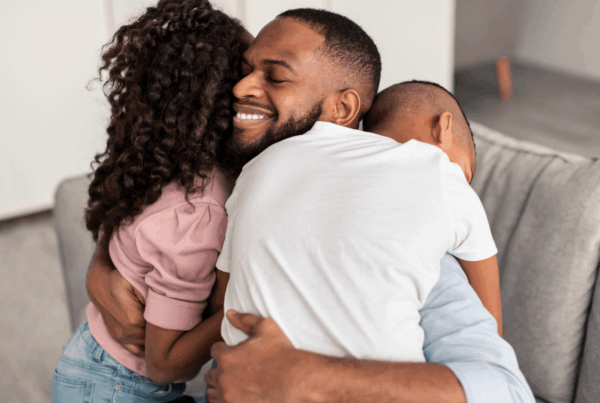 Man hugging his children with a smile on his face after regaining custody of his children.