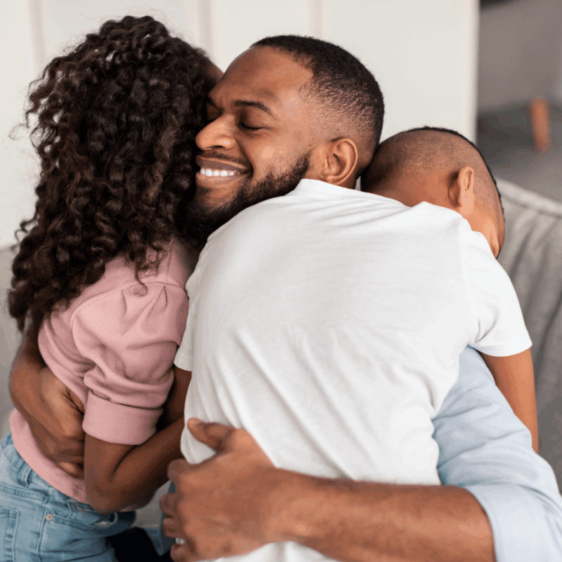 Man hugging his children with a smile on his face after regaining custody of his children.