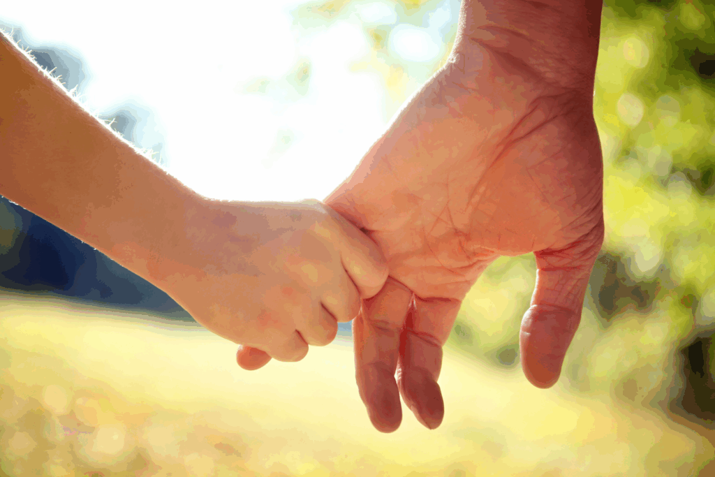 Parent and child holding hands outdoors, symbolizing family connection and support.
