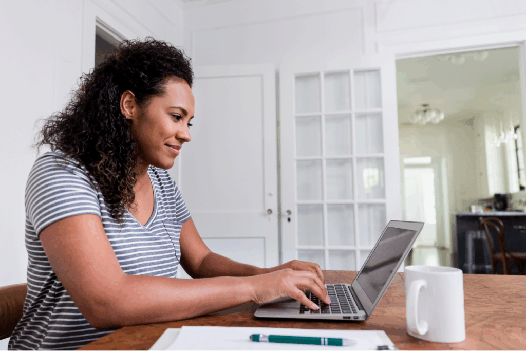 Smiling stay-at-home mom planning divorce on laptop at home.