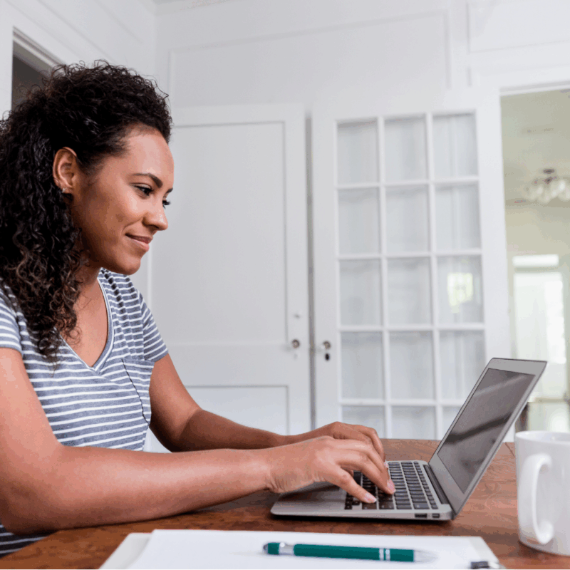 Smiling stay-at-home mom planning divorce on laptop at home.