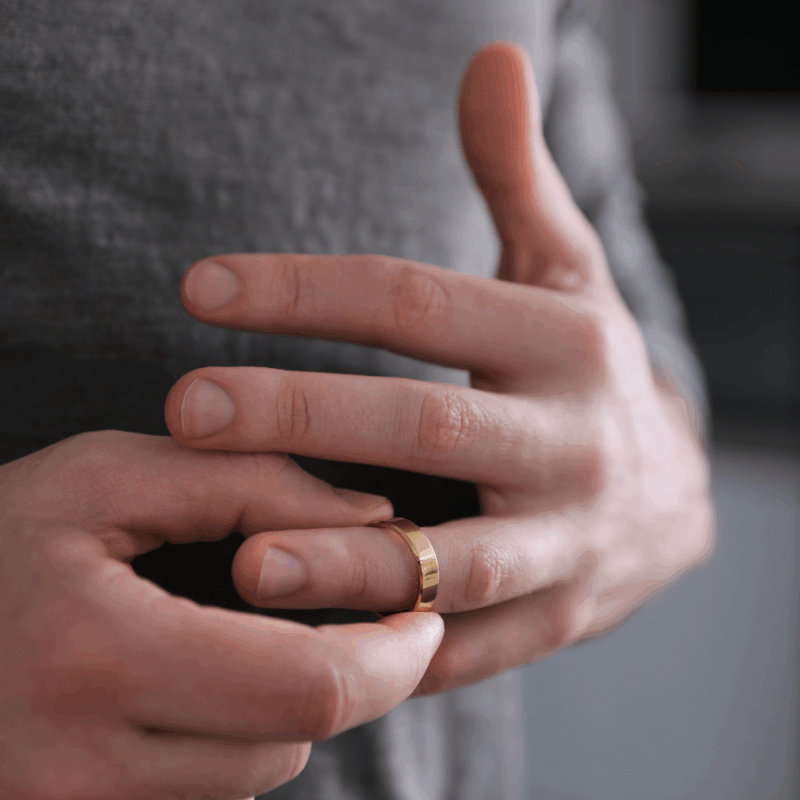 Man removing wedding ring, symbolizing divorce and relationship changes.