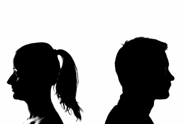 Silhouettes of a man and woman facing away from each other, representing emotional distance in a silent divorce.
